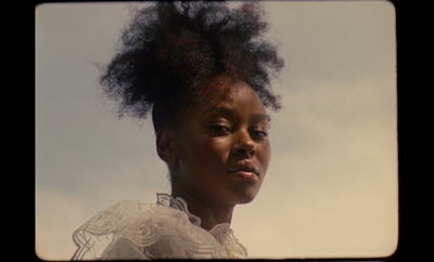 a woman with a very large afro standing in front of a blue sky