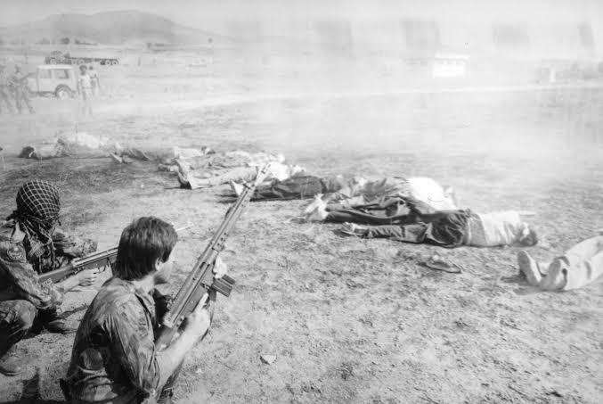 a black and white photo of a group of men with guns