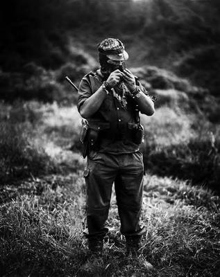 a man standing in a field holding a rifle