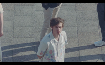 a young boy walking down a sidewalk next to a group of people