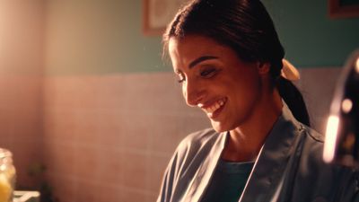 a woman smiles as she prepares food in a kitchen