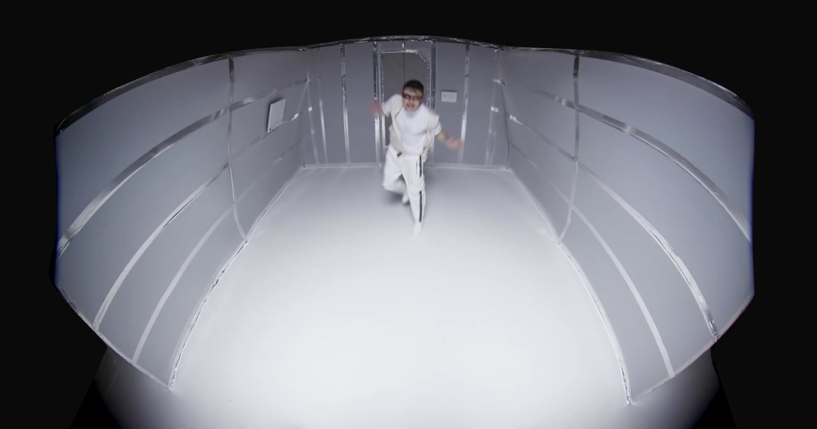 a man walking down a hallway in a white suit