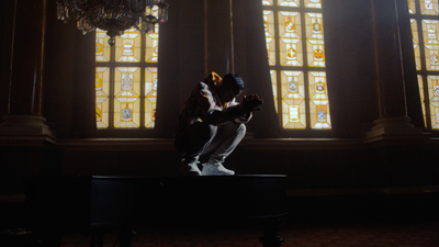 a man sitting on top of a piano in front of a stained glass window