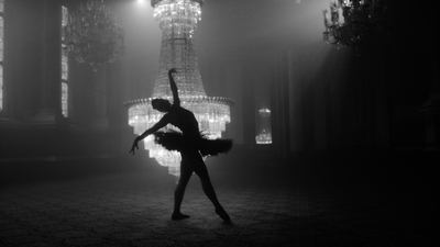 a ballerina in front of a chandelier in a black and white photo