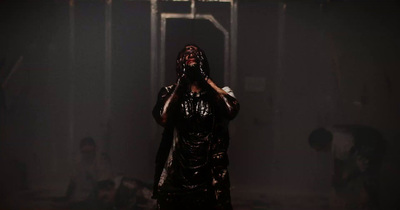 a woman in a dark room covering her face with her hands