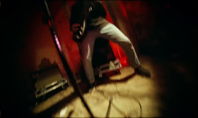 a man holding a baseball bat while standing in front of a red wall