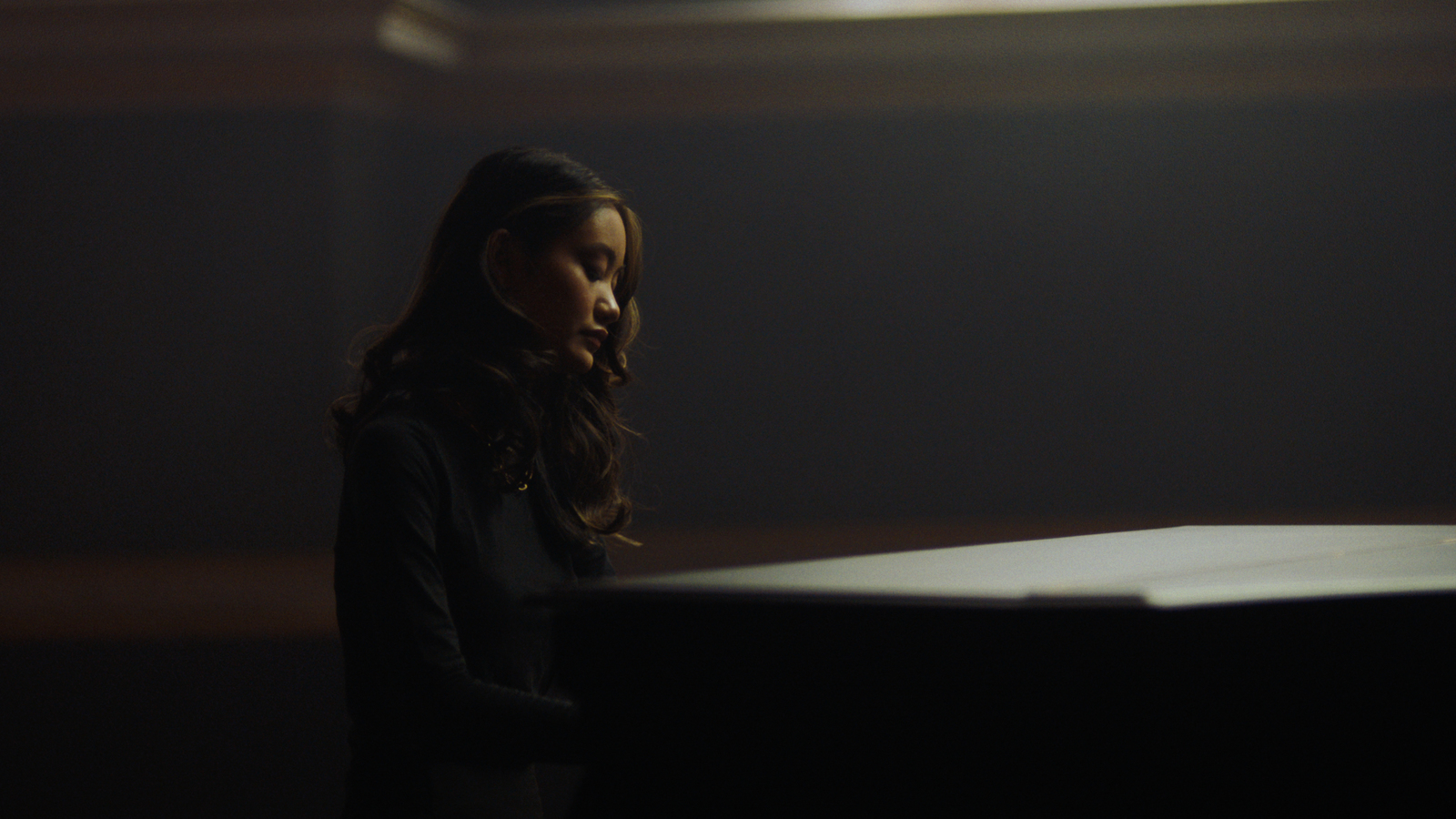 a young girl standing in front of a piano