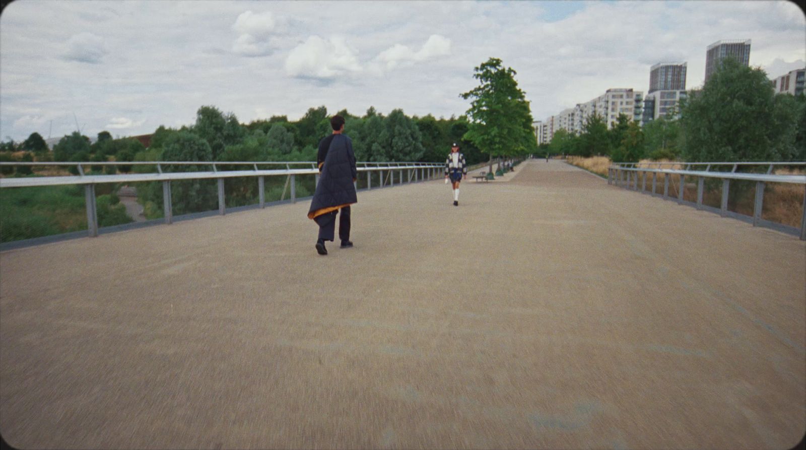 two people walking across a bridge in a city