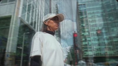 a woman wearing a hat and a white shirt standing in front of a tall building