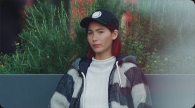 a young man wearing a black and white jacket and a hat