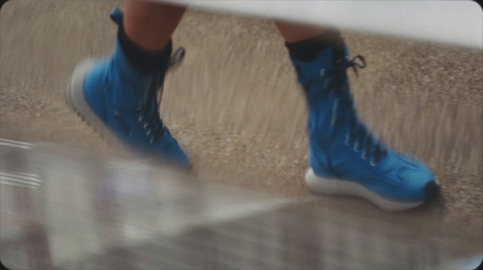 a person in blue sneakers walking on a sidewalk