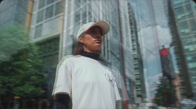 a woman in a baseball cap standing in front of a tall building