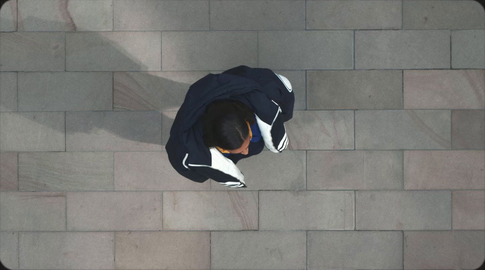 a man in a hoodie sitting on a brick walkway