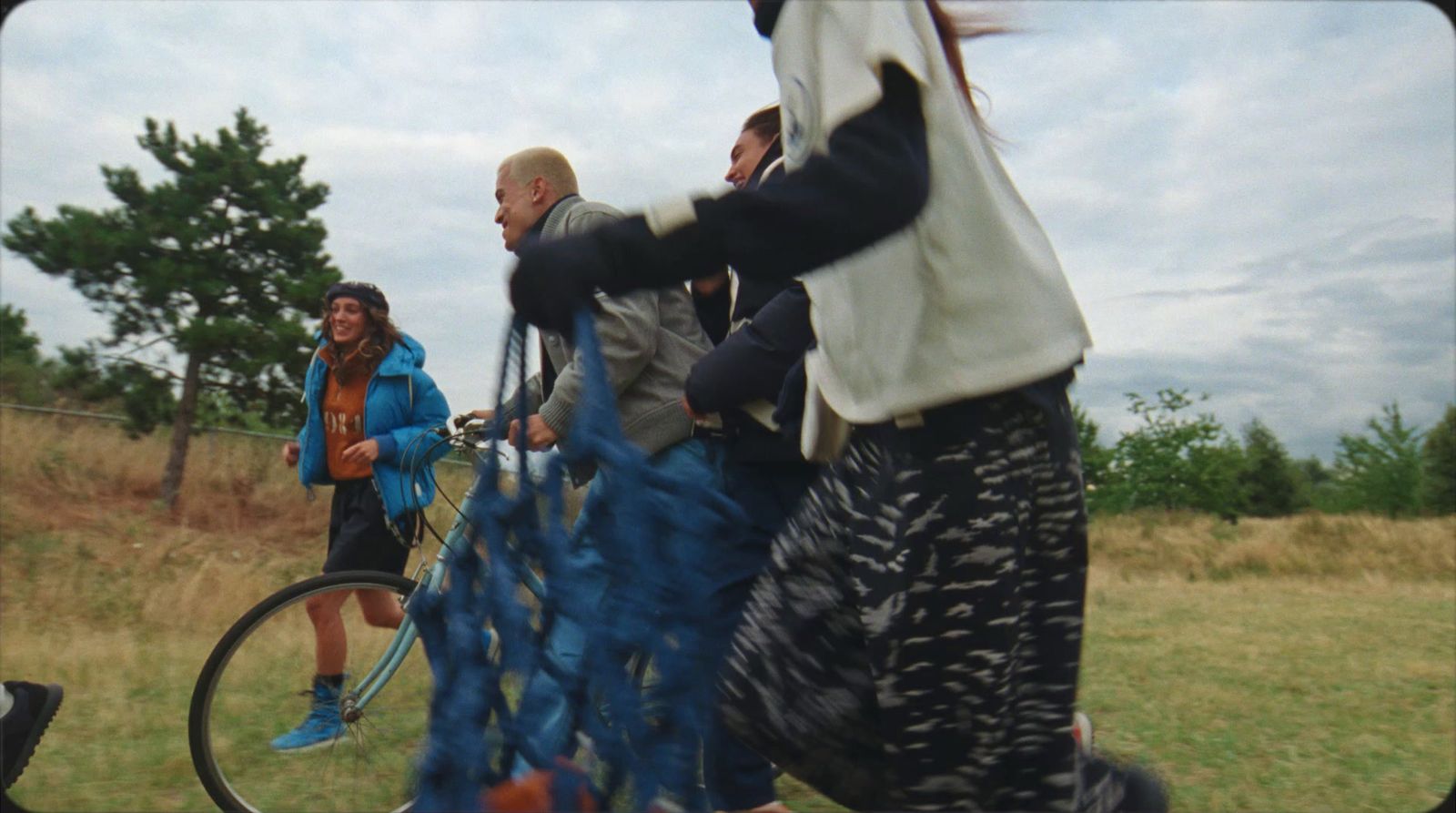 a group of people riding bikes down a grass covered field