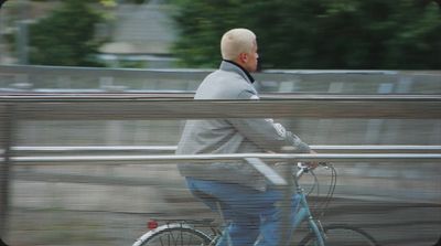 a man riding a bike down a street next to a fence