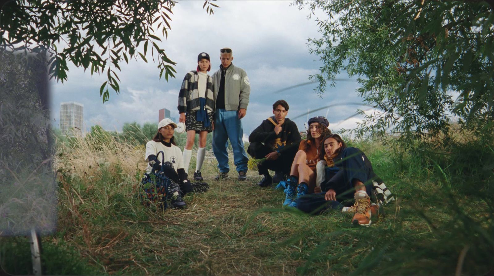 a group of people sitting in the grass under a tree