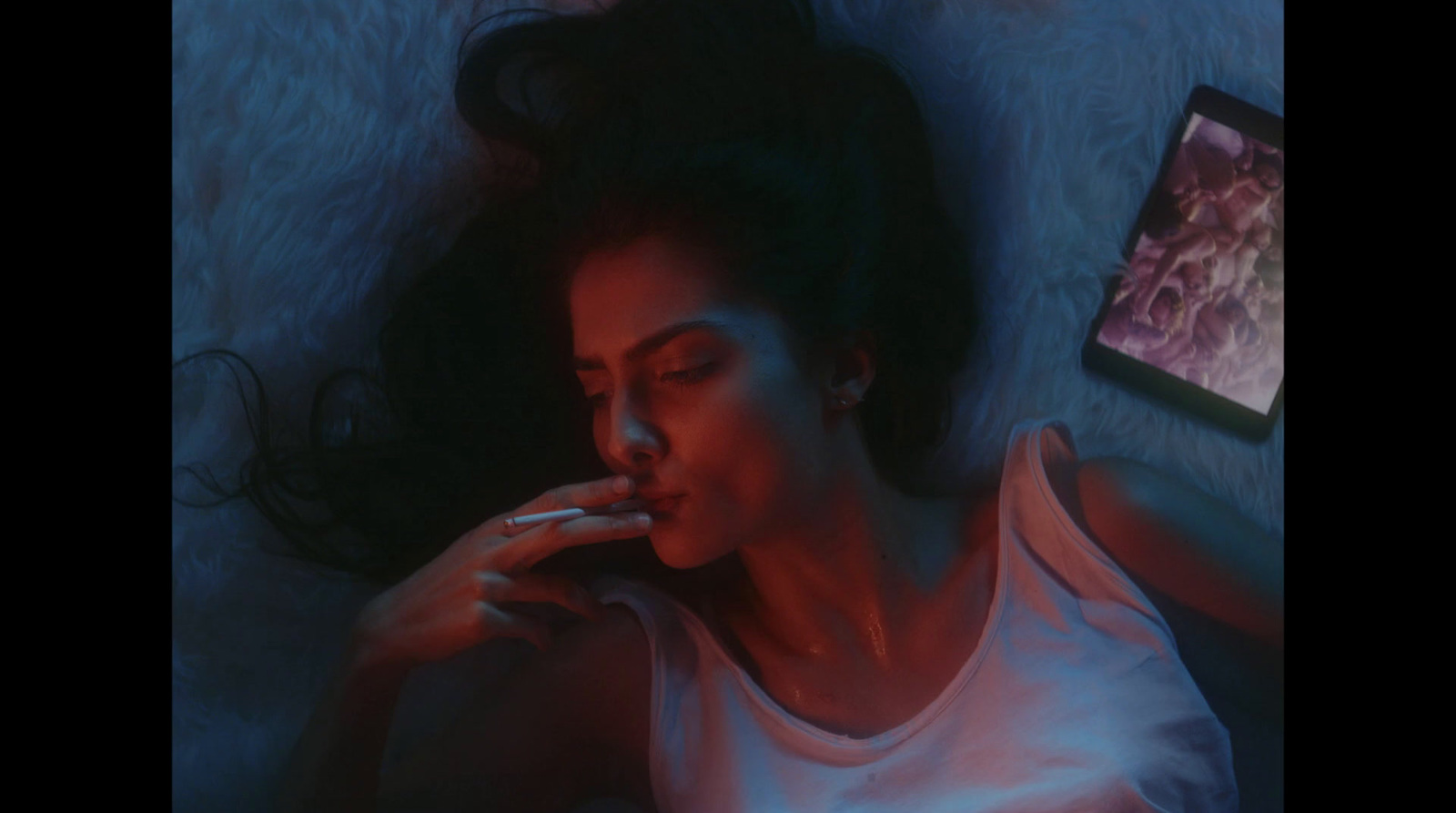 a woman laying on a bed smoking a cigarette