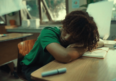 a young woman sitting at a desk with her head on her hands