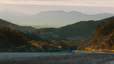 a couple of people riding on the back of a motorcycle down a road