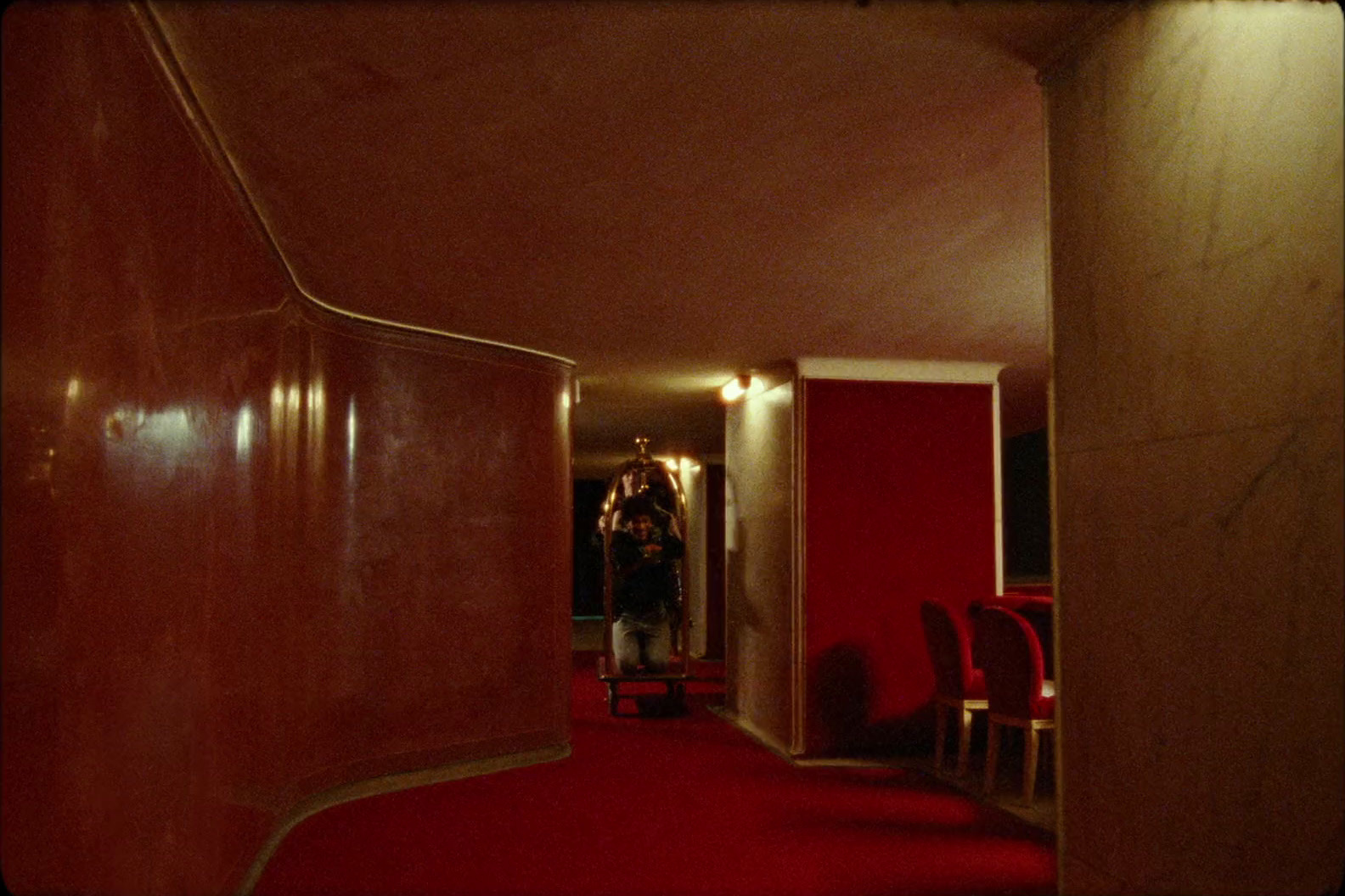 a hallway with a red carpet and red chairs