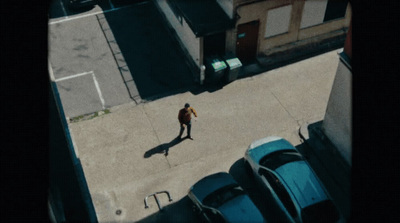 a man walking down a street next to parked cars