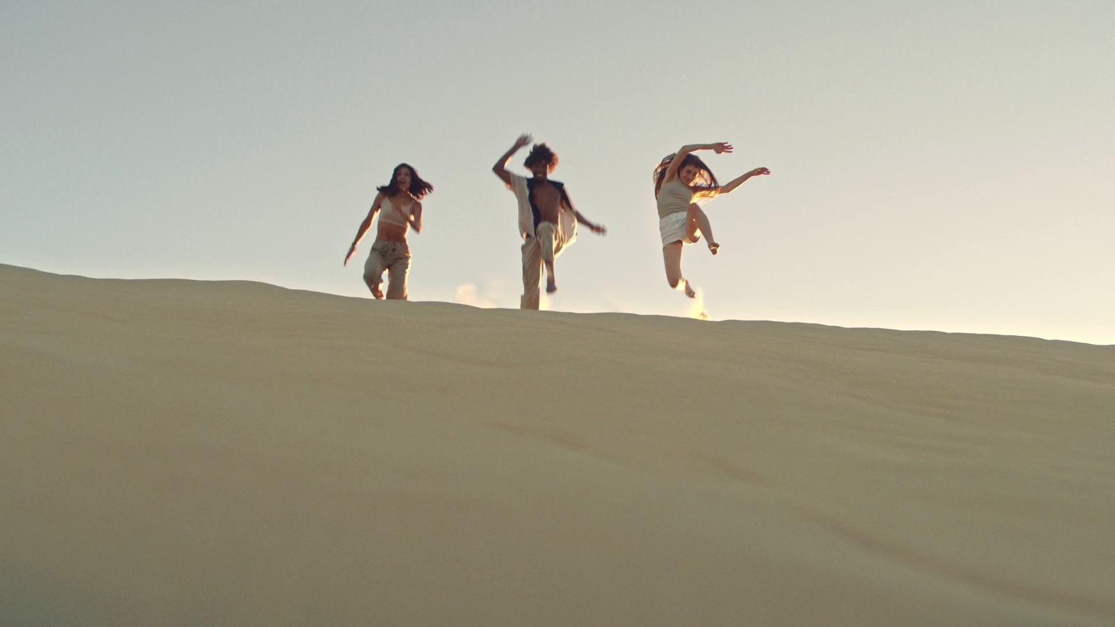 a group of people standing on top of a sandy hill