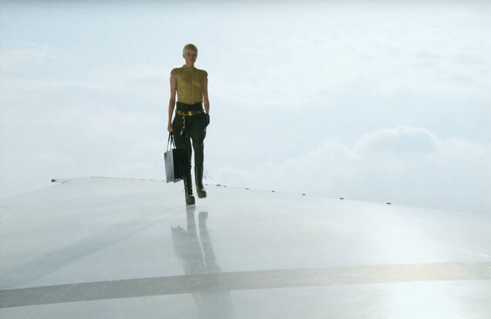 a woman standing on top of a roof holding a suitcase