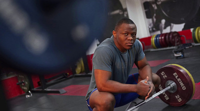 a man squatting down with a barbell in his hand