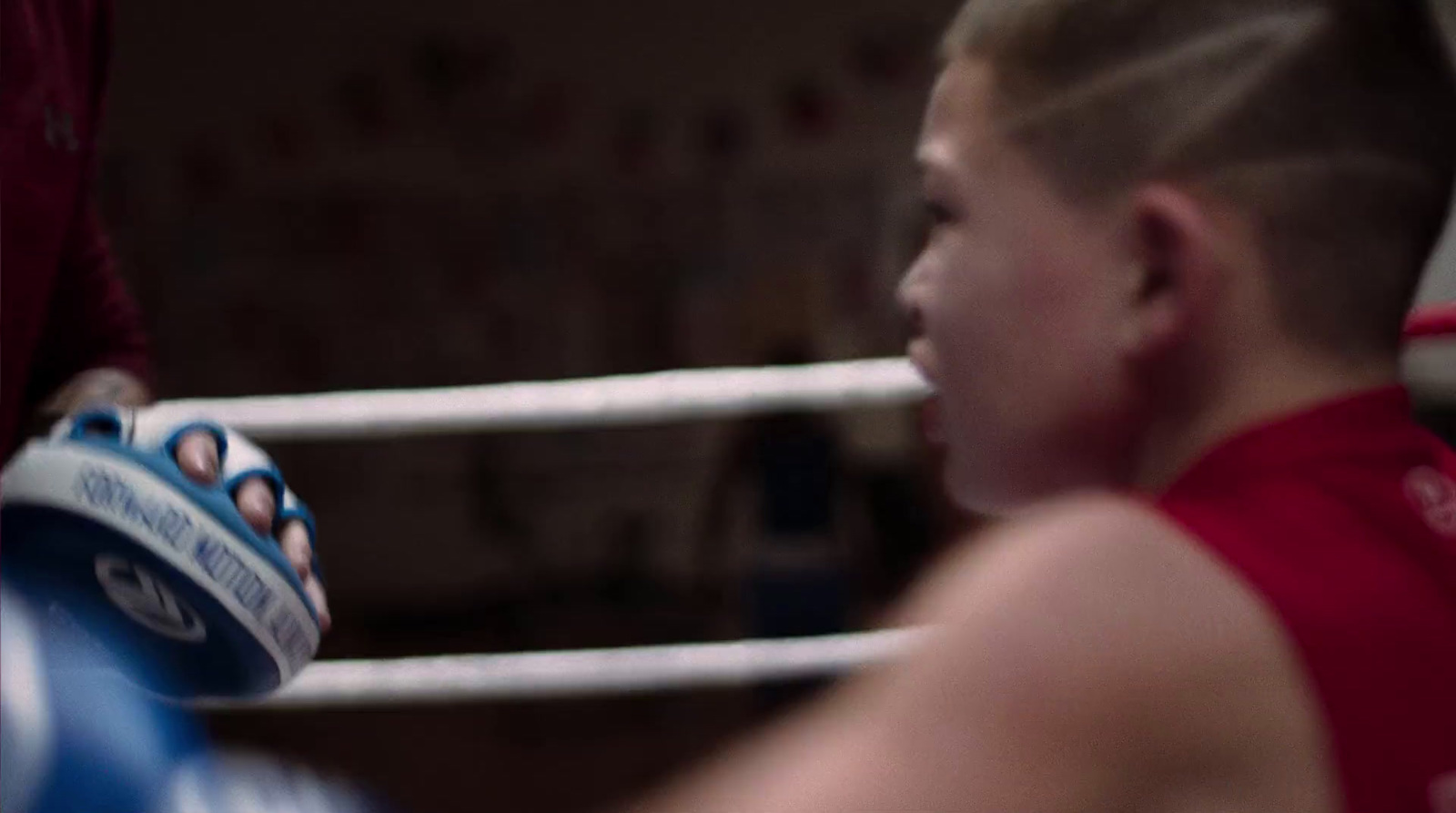 a young boy wearing a red shirt and a blue and white boxing glove