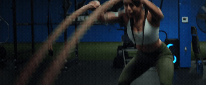 a woman in a white tank top and green leggings in a gym