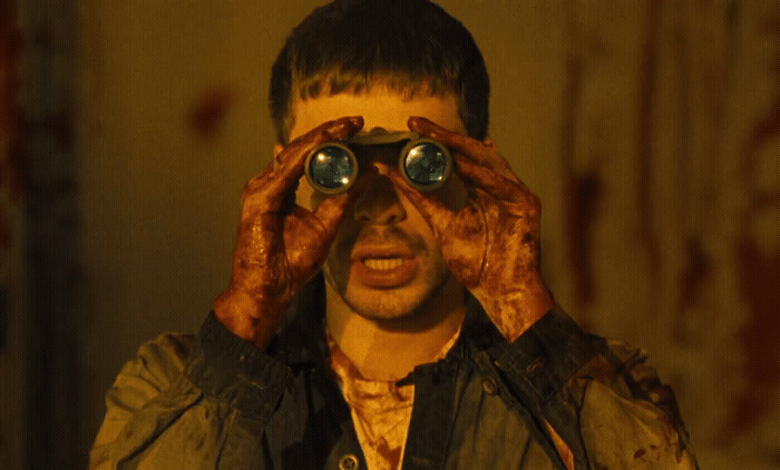 a man with his hands on his face looking through a pair of binoculars