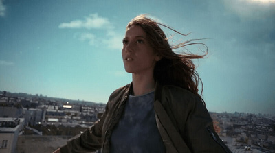 a woman with long hair standing on top of a roof