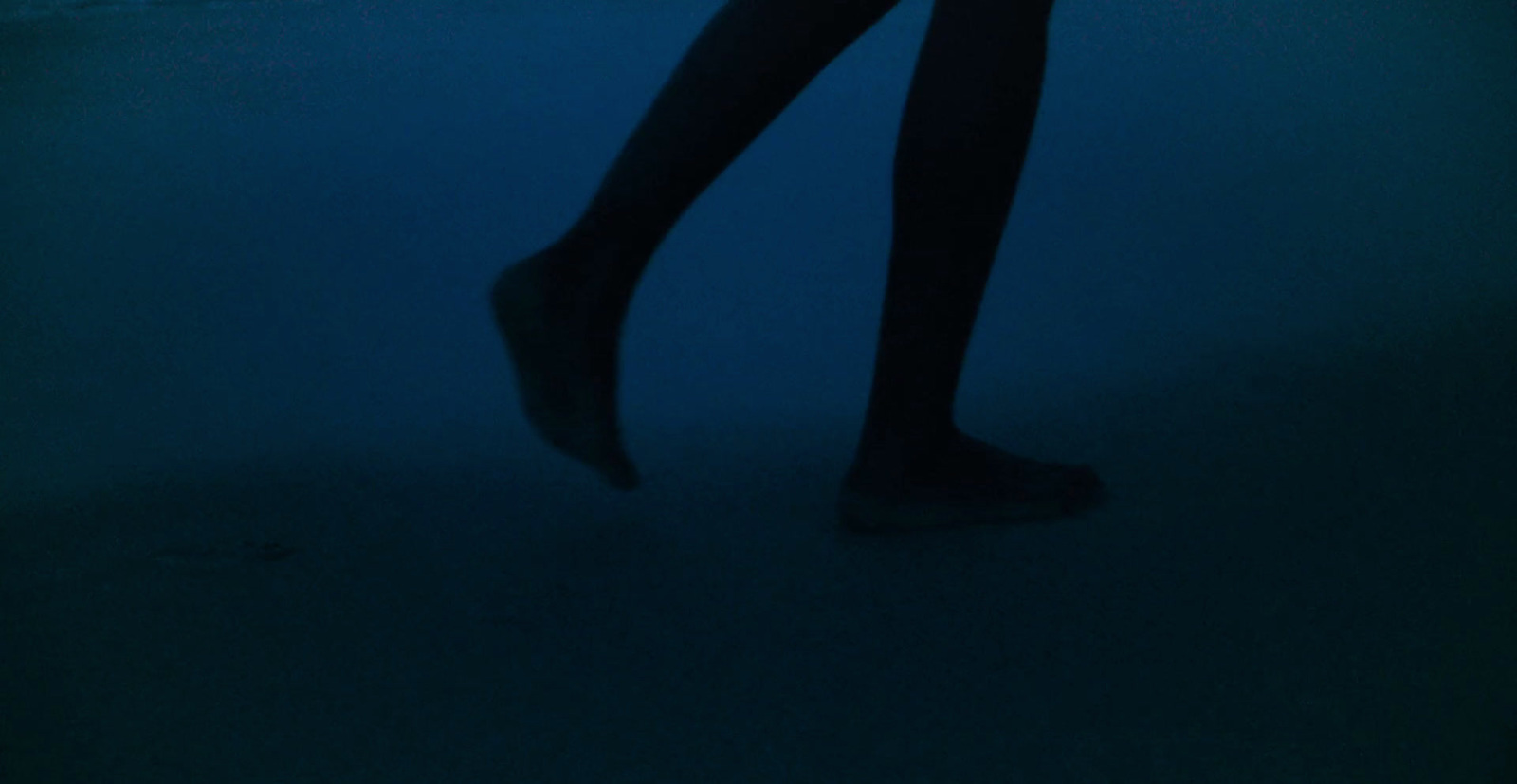 a woman standing in the dark with her legs crossed