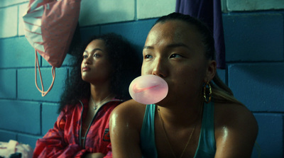 two women sitting next to each other with a bubble in their mouth