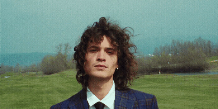 a man with curly hair wearing a suit and tie