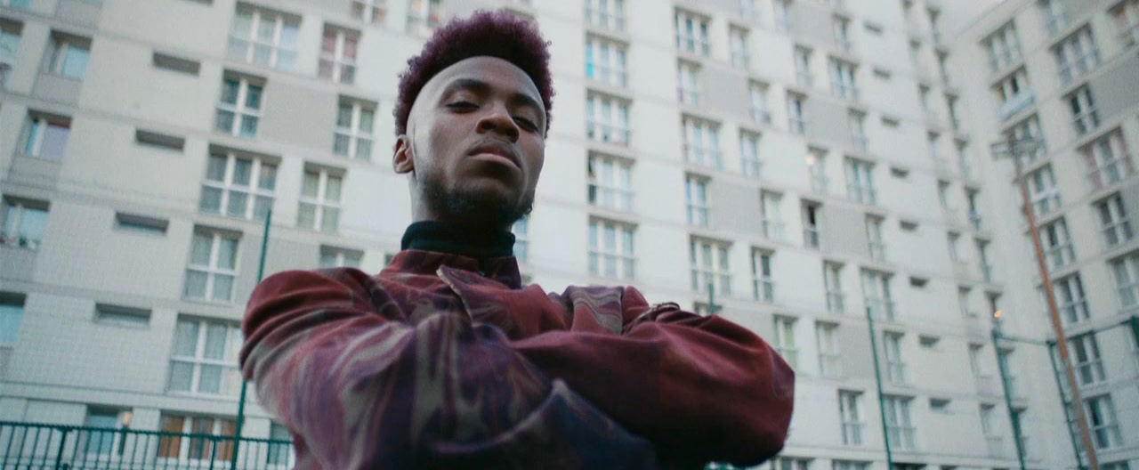 a man with a mohawk standing in front of a tall building