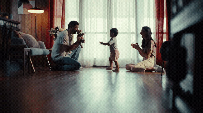 a man, woman, and child sitting on the floor in front of a window