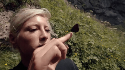 a woman pointing a finger at a butterfly