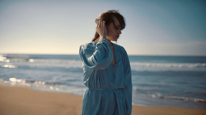 a woman in a blue dress standing on a beach