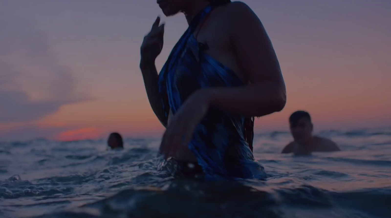 a woman standing in the ocean at sunset