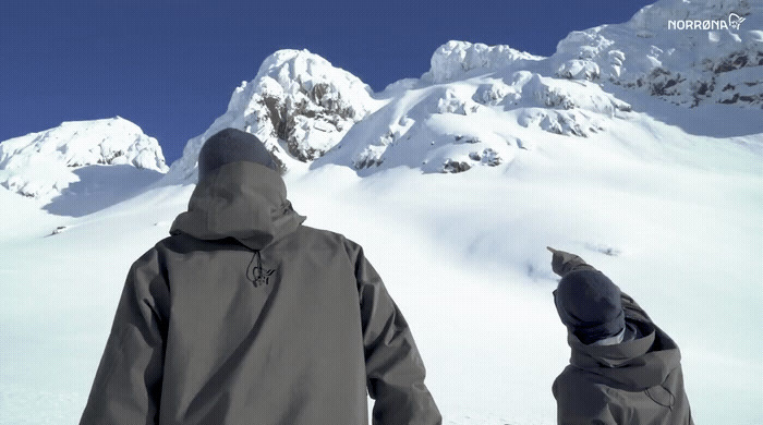 a couple of people standing on top of a snow covered slope