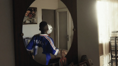 a young boy in a blue uniform looking into a mirror