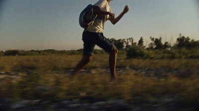 a man walking through a field with a backpack on his back