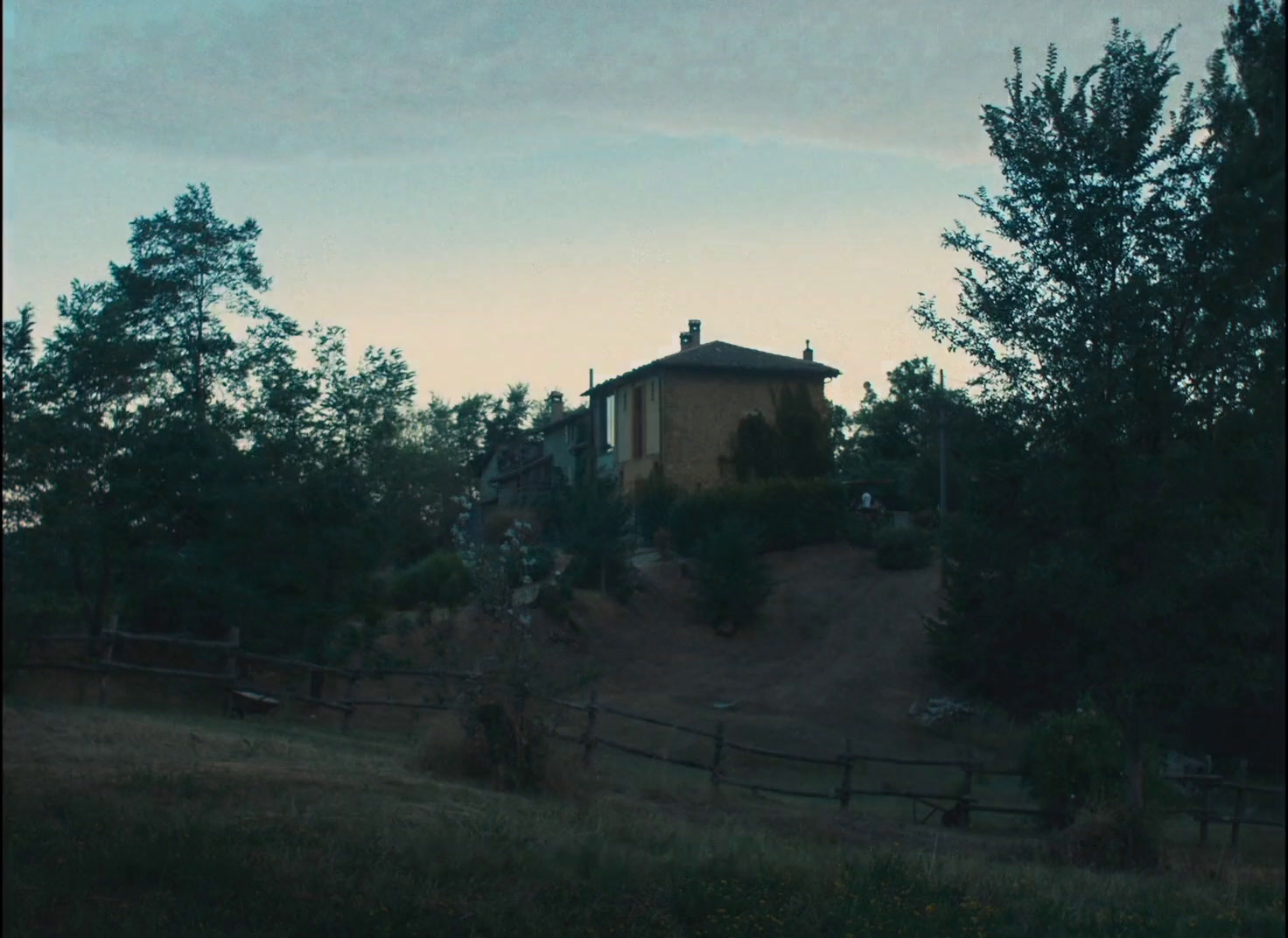 a house sitting on top of a hill surrounded by trees