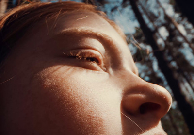 a close up of a person's face with trees in the background