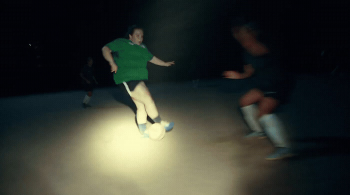 a man in a green shirt kicking a soccer ball