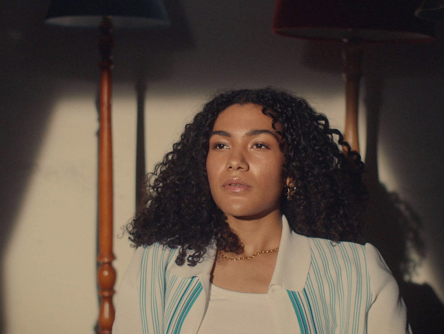 a woman with curly hair standing in front of a lamp