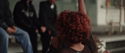 a woman with red hair raising her hand in the air