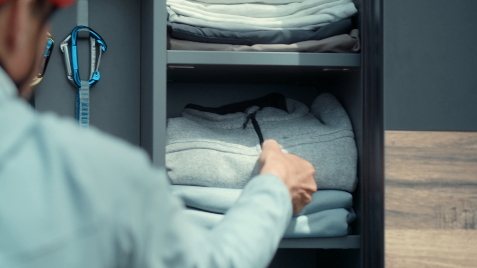 a man in a blue shirt is looking at some folded clothes