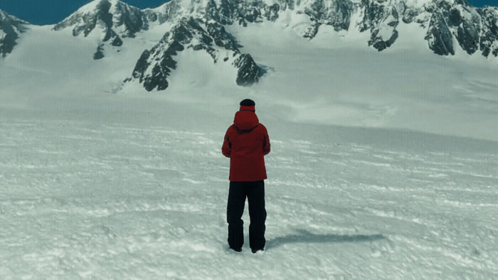 a person standing in the snow in front of a mountain